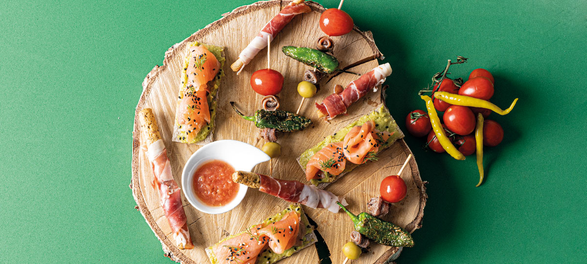 Gilda de tomate cherry, grissini de jamón ibérico y tosta de semillas con guacamole y salmón